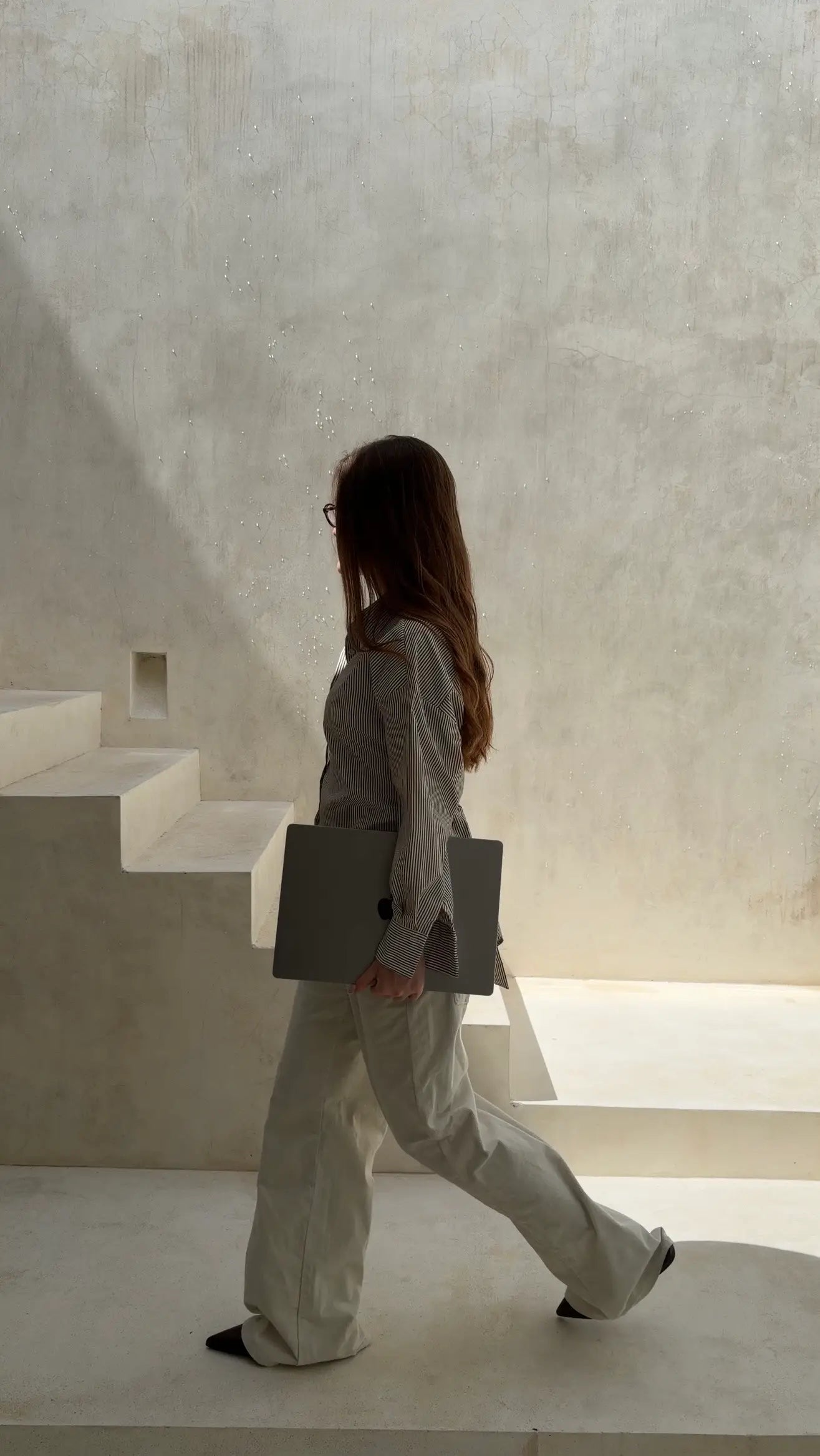 Person walking with a bag in a minimalistic architectural setting